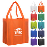 An orange non-woven shopping bag with two handles and a logo, surrounded by bags in various colours.