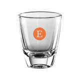 A clear glass shot glass with a solid base and an orange circular logo containing the letter "E."