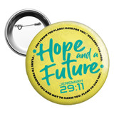 A round 75mm button badge in yellow, featuring a logo and text in teal.