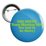 A 25mm round button badge in blue with a metal back and pin, featuring vibrant green text.