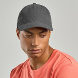 A grey recycled corduroy cap with a curved brim, worn by a person in a coral shirt. The cap features a logo.