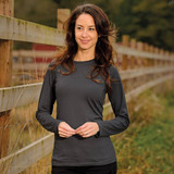 A woman models a long-sleeve, charcoal grey tee with a simple design, set against a natural outdoor backdrop.