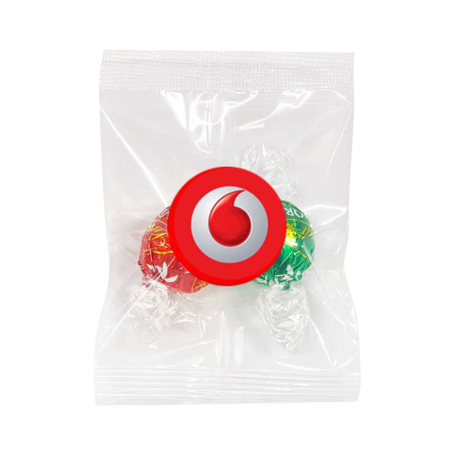 Two Lindt chocolate balls in red and green packaging, sealed in a clear plastic bag with a logo. Two Lindt chocolate balls in red and green packaging, sealed in a clear plastic bag with a logo.