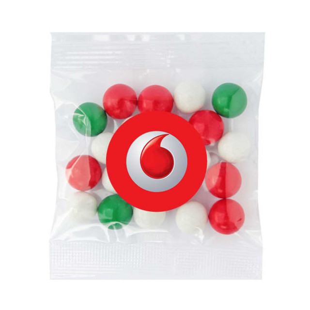 A sealed clear bag containing red, green, and white chocolate balls, with a logo on the packaging. A sealed clear bag containing red, green, and white chocolate balls, with a logo on the packaging.