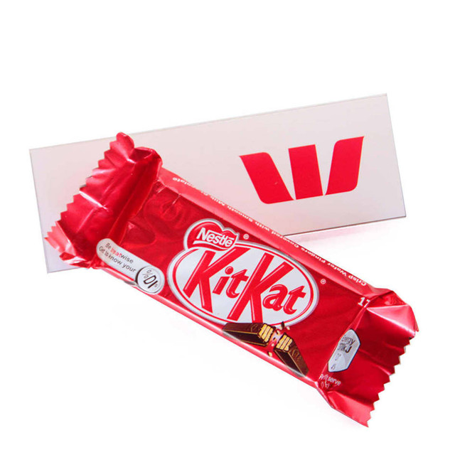 A red and gold two-finger Kit Kat chocolate bar placed on a white rectangular card featuring a logo. A red and gold two-finger Kit Kat chocolate bar placed on a white rectangular card featuring a logo.