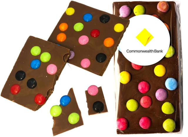 Premium chocolate bar with colourful spotty candy dots in vibrant colours on a brown chocolate background, with packaging and logo.