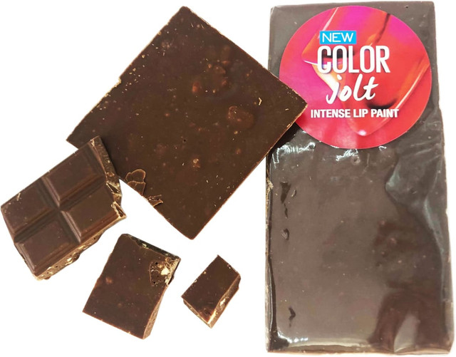 A block of dark chocolate with several pieces broken off, featuring a round branding logo.