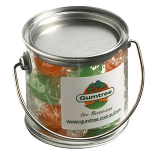 A small transparent PVC bucket filled with colourful boiled lollies, featuring a metal handle and a logo on the side.