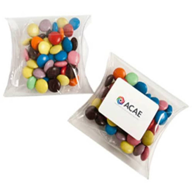 A pillow pack containing colourful choc beans, featuring a branding sticker on the front.