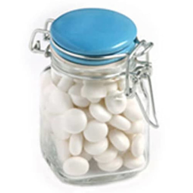 A clear glass jar with a blue lid filled with white chewy mints. The jar features a locking mechanism.