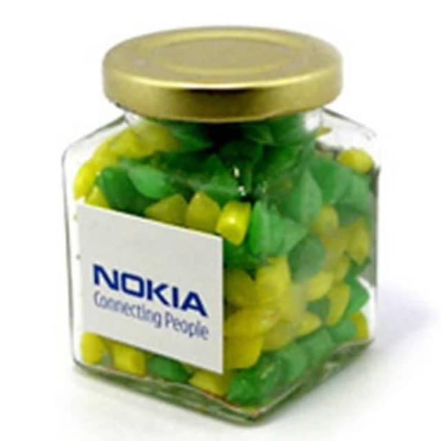 A glass square jar filled with green and yellow humbugs, featuring a logo on the front.