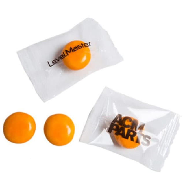 Individually wrapped orange chewy fruit candies, displayed alongside their transparent packaging.
