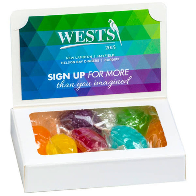 A white box containing colourful boiled lollies arranged inside, with a lid displaying a green and blue geometric design.