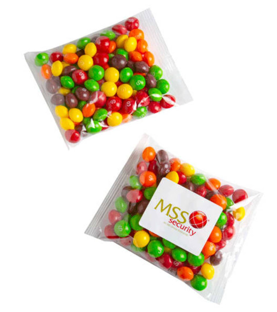 A clear bag filled with colourful chewy fruit candies, featuring red, yellow, green, orange, and brown sweets. The bag has a logo.