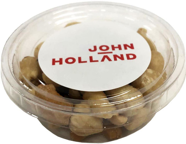 A clear container filled with mixed nuts, showcasing light and dark brown varieties. Includes a logo on the lid.