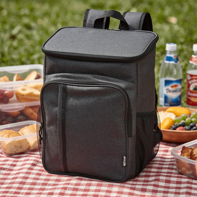 A grey picnic cooler backpack with a front pocket, beside containers of food and drinks on a picnic blanket.
