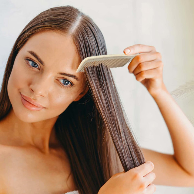A woman is using a Lynx Wheat Fibre Comb to style her long, straight hair. A woman is using a Lynx Wheat Fibre Comb to style her long, straight hair.