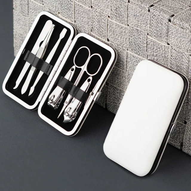 A sleek white manicure set case containing stainless steel tools like scissors, clippers, and tweezers.