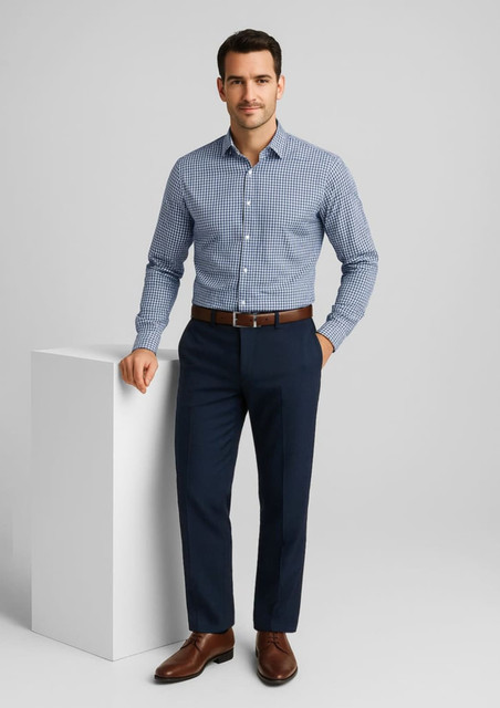 A man wearing a blue checked shirt and navy flat front pants, standing next to a white display. The pants have a branding logo.