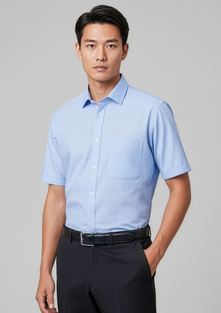 A light blue short sleeve button-up shirt with a chest pocket, tucked into dark trousers, featuring a logo.