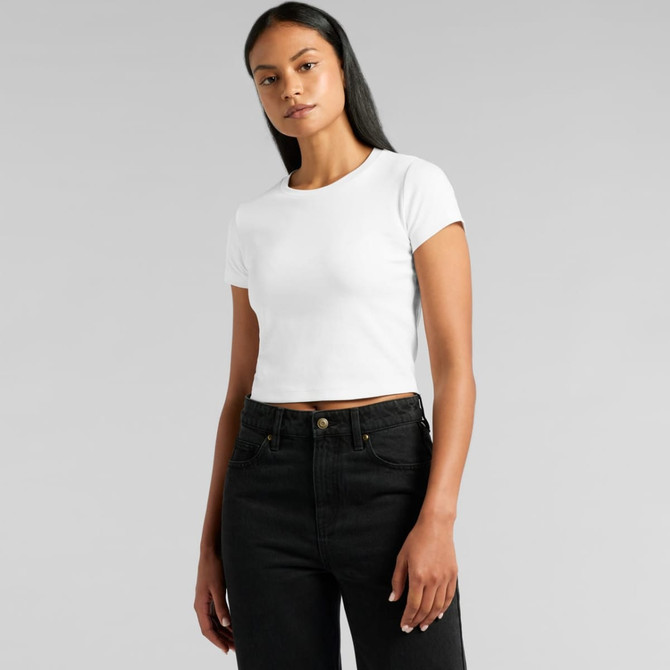 A white cropped t-shirt displayed on a model wearing black jeans, featuring a simple design and a logo.