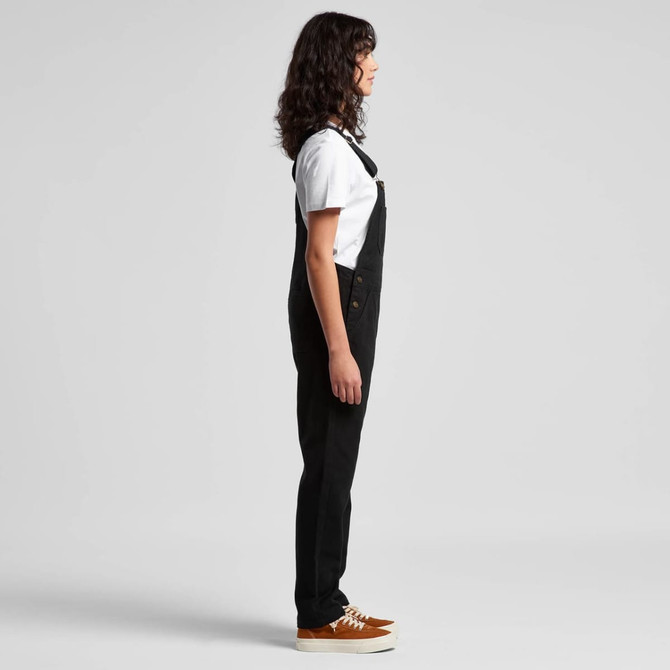 Black canvas overalls worn with a white T-shirt and brown shoes, displayed in a side view. The outfit features a logo.