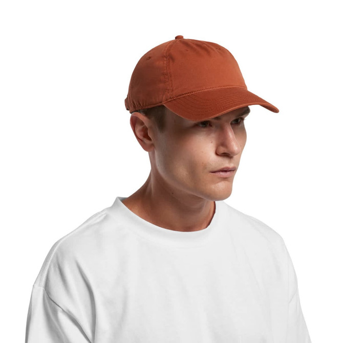 A five-panel cap in a rust colour worn by a model, featuring a logo on the front.
