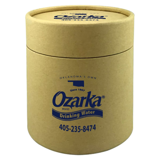 A drink bottle in a small, cylindrical gift tube made of brown cardboard, featuring a logo and blue text.