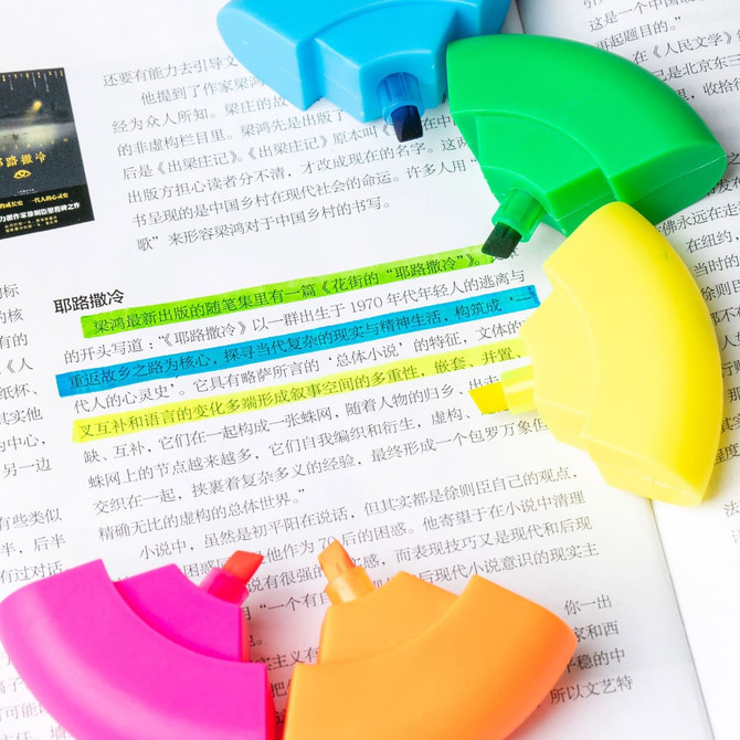 A set of circular highlighters in blue, green, yellow, pink, and orange, placed on a page of text.