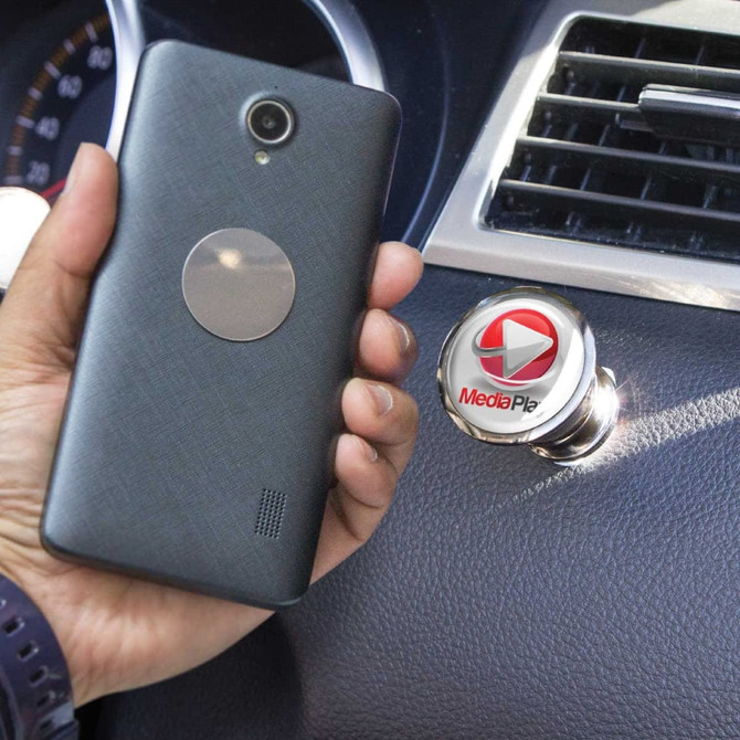 A black smartphone with a magnetic attachment beside a metallic car phone holder with a logo on it.