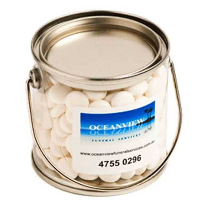 A small silver bucket contains white mints. The bucket features a handle and a logo on the side.