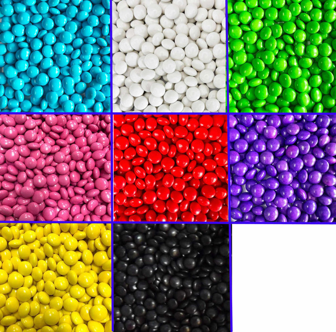 A collection of choc beans in various colours, including blue, white, green, pink, red, purple, black, and yellow.
