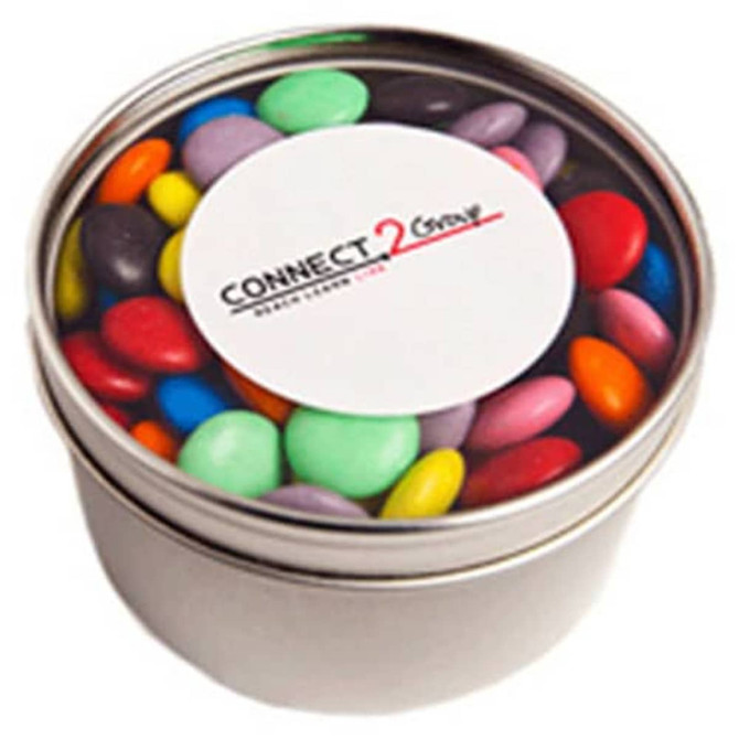 A small round tin filled with colourful chocolate beans, featuring a lid with a logo.