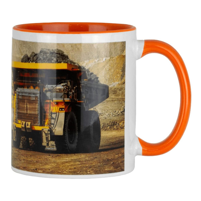 A ceramic mug with a white body and an orange handle, featuring an image of a large mining truck.