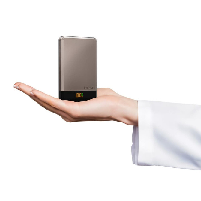 A compact silver and black wireless power bank held in a hand, featuring a small display.