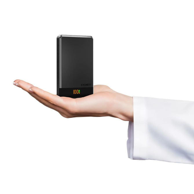 A hand holding a compact black power bank with a digital display and branding on one side.