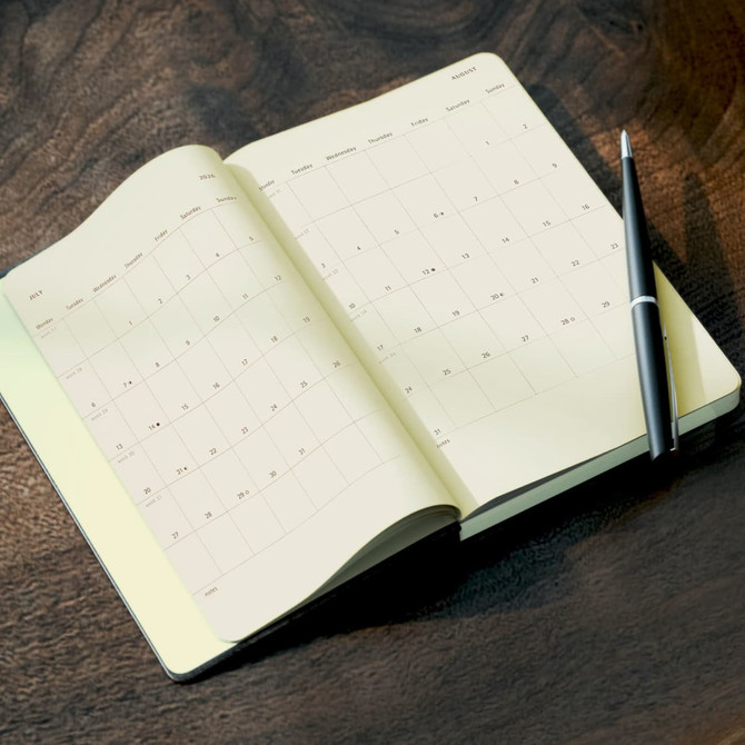 An open Moleskine 2026 Daily Planner with a black pen resting on it, featuring a light cream interior.