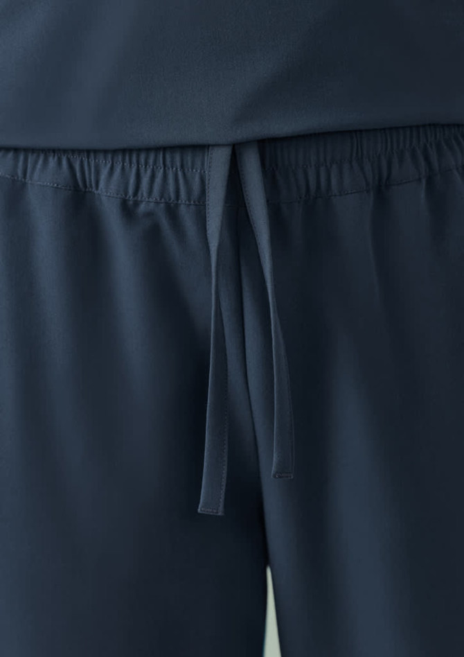 A close-up of navy women's jogger scrub pants featuring an elastic waistband and drawstring detail.
