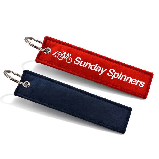 A red and navy woven keytag with a ring, featuring a logo on the red tag.