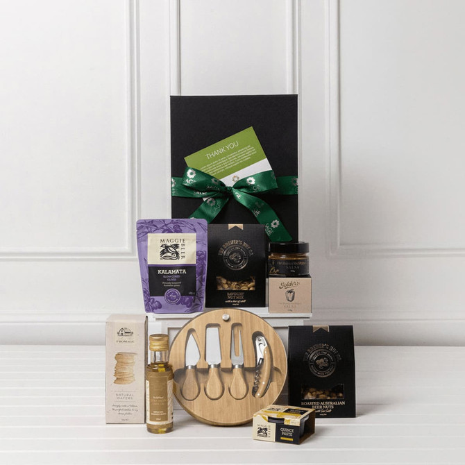 A gourmet gift pack featuring a wooden platter, condiments, oils, snacks, and a variety of packaging, all in black.