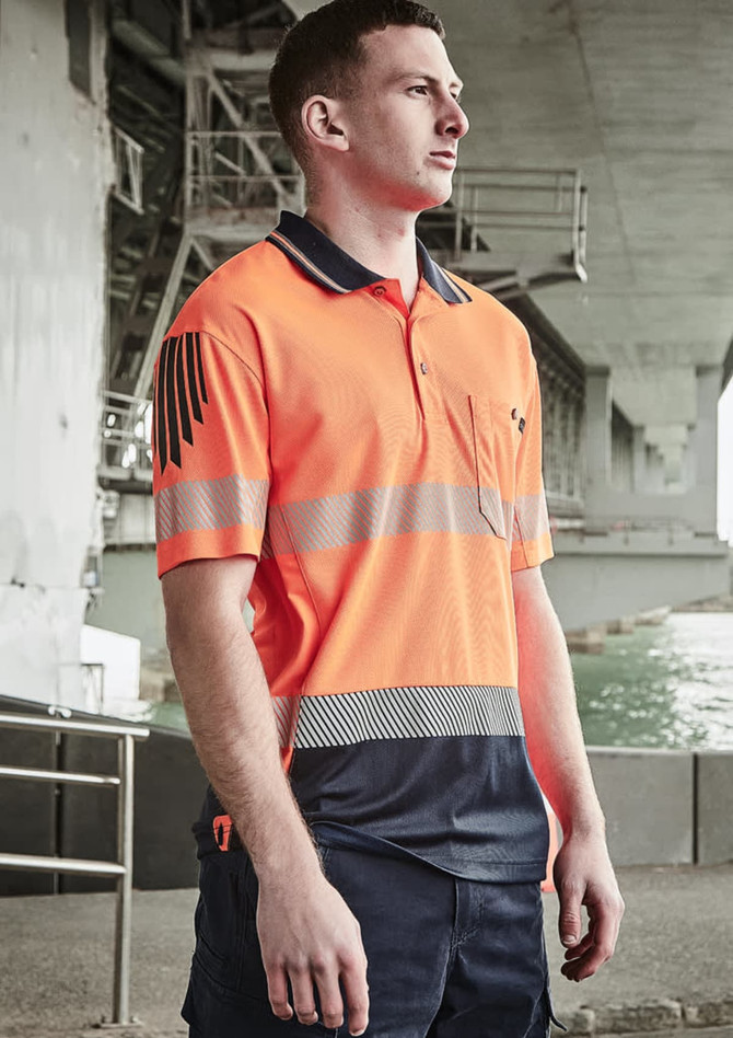 A man wearing a high-visibility orange and navy short sleeve polo with segmented reflective tape and a logo.
