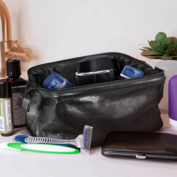A black leather toiletry bag containing various personal care items, including bottles, a razor, and a wallet.
