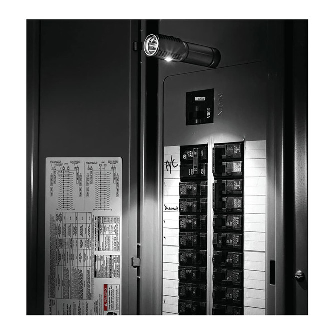 A sleek silver LED torch illuminating a dark electrical circuit board, mounted beside a black panel.