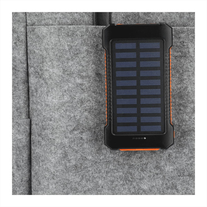 A black and orange solar power bank with a textured surface, placed in a grey felt pocket.
