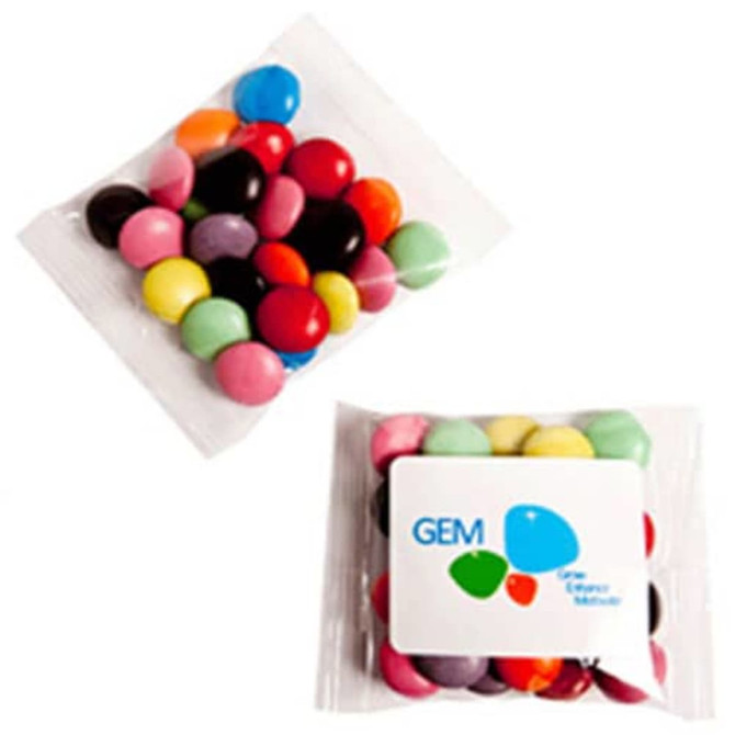 A transparent bag containing colourful chocolate beans in various shades, with a logo on the bag.