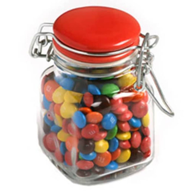 A glass clip lock jar with a red lid filled with colourful M&Ms in various shades. Comes with branding.