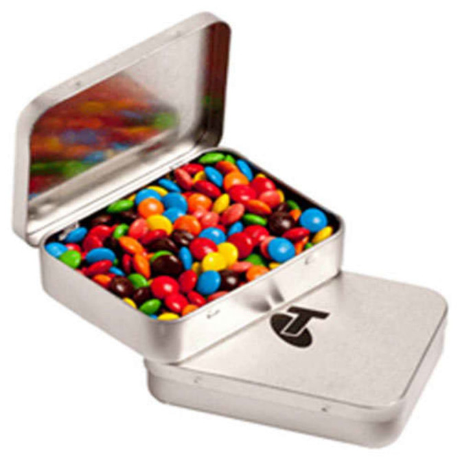 A rectangular silver tin filled with colourful M&Ms, featuring a logo on the lid.