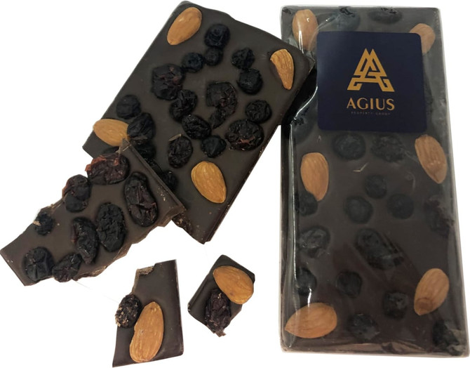 A dark chocolate bar with almonds and dried fruits, partially broken, featuring a branded logo.
