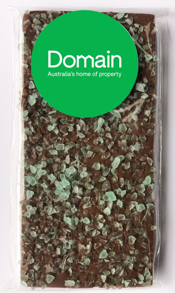 Premium milk chocolate bar featuring a layer of peppermint crystals, enclosed in clear wrapping with a logo.