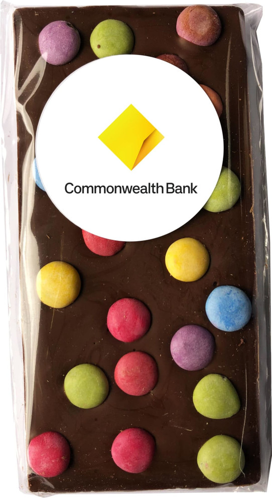 A milk chocolate bar featuring colourful spotty decorations, wrapped in plastic with a branding logo.